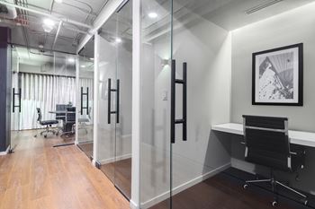 A modern office with glass walls and a wooden floor.